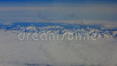 从鸟瞰`飞机窗口的地平线和云层和白雪覆盖的山脉。